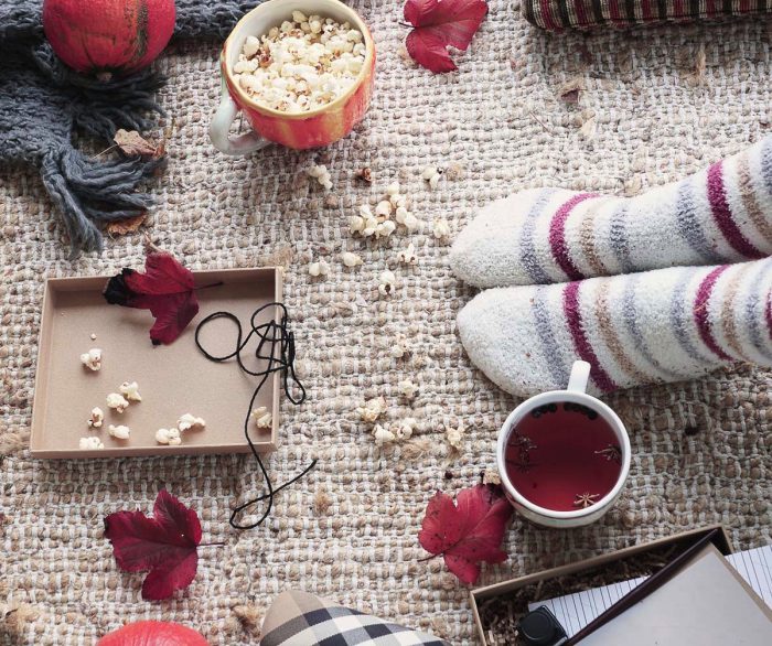 Herbstdekor mit Tee, dicke Socken und Popcorn